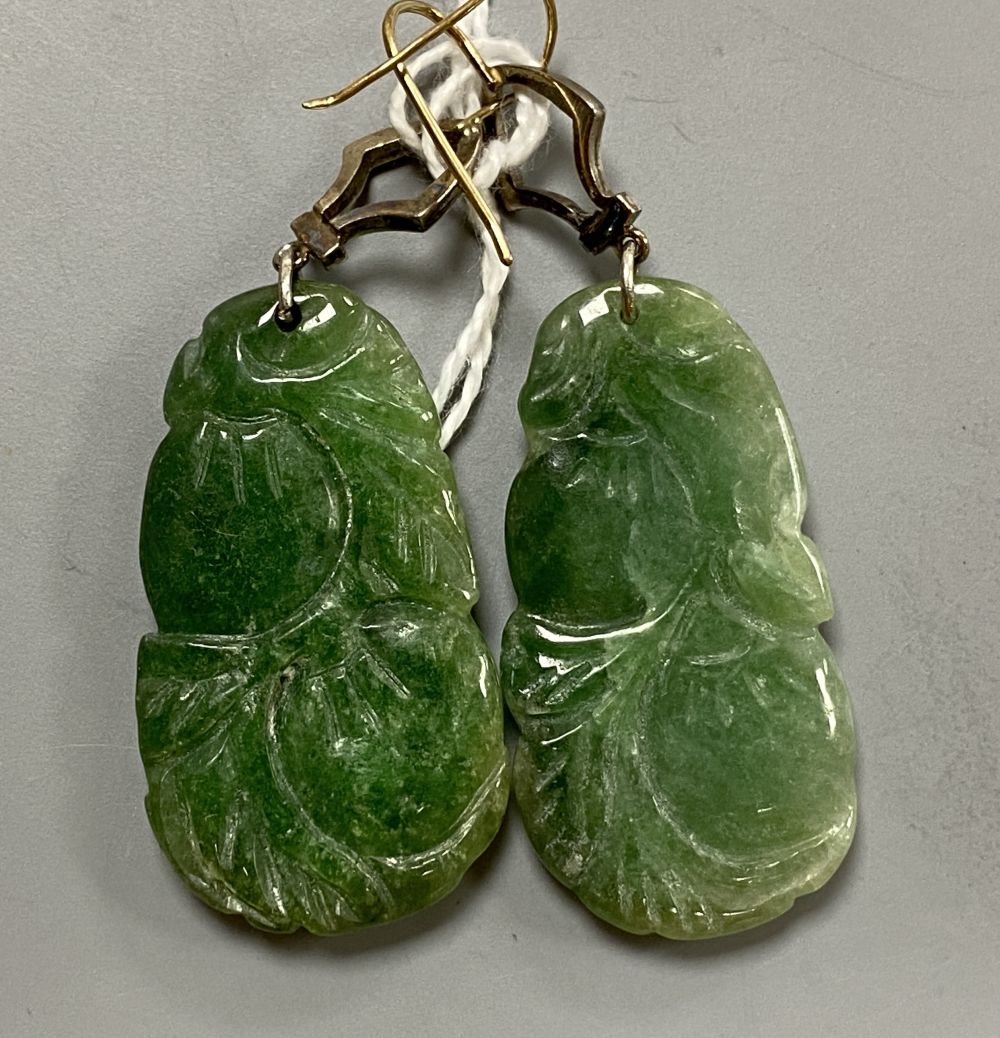 A pair of white and yellow metal, diamond chip set carved jade drop earrings, jade 35mm, gross 14.7 grams.